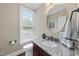 Charming powder room featuring granite countertops, a decorative mirror, and updated fixtures at 401 Clingstone Ct, Cary, NC 27519