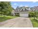 View of a gray two-story home with a two-car garage and wide concrete driveway and manicured lawn at 401 Clingstone Ct, Cary, NC 27519