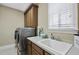 Well-equipped laundry room with stainless steel washer and dryer, sink, and ample cabinet space at 401 Clingstone Ct, Cary, NC 27519