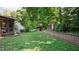Picturesque backyard featuring a lush lawn, mature trees, and charming outbuildings at 4713 Little Falls Dr, Raleigh, NC 27609