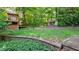 Spacious backyard with tiered retaining wall, mature trees, and charming outbuildings at 4713 Little Falls Dr, Raleigh, NC 27609