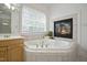 Luxurious bathroom featuring a jacuzzi tub, fireplace, and large window for natural light at 4812 Cornoustie Ct, Holly Springs, NC 27540