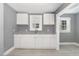 An airy kitchen with white cabinets, gray countertops, and gray vinyl flooring at 518 Avon Ave, Burlington, NC 27215