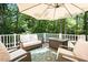 Comfortable seating area on the back deck with wooded views, umbrella, and coffee table at 5601 Jomali Dr, Durham, NC 27705
