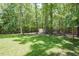 Lush backyard with shade trees and a storage shed at 5601 Jomali Dr, Durham, NC 27705