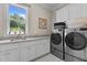 Bright laundry room featuring modern washer and dryer, granite counters, and ample cabinet space at 60 Hartwood Ln, Youngsville, NC 27596