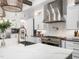 A modern kitchen featuring white cabinets, a stainless steel range hood, and a spacious quartz countertop island at 604 Dappled Pine Ave, Durham, NC 27713
