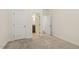 Neutral bedroom with carpeted floors, white walls, and two open doors to the ensuite bathroom at 605 Hampton Crest Ct, Fuquay Varina, NC 27526