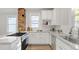 Updated kitchen showcasing white cabinets, granite counters, stainless appliances, and brick accent wall at 610 N Driver St, Durham, NC 27703