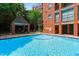 Beautiful clear community pool with a covered patio and chairs is surrounded by lush greenery and brick architecture at 620 Martin Luther King Jr Blvd # Apt 502, Chapel Hill, NC 27514