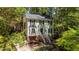 Charming two-story home with light green siding, black shutters, and landscaped front yard, nestled within mature trees at 6904 Sandringham Dr, Raleigh, NC 27613