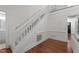 Bright foyer showcasing hardwood floors and a staircase with white wood railing and carpeted steps at 6904 Sandringham Dr, Raleigh, NC 27613
