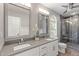 Modern bathroom with dual sinks, vanity, and tiled shower with glass door at 8721 Springhouse Ln, Raleigh, NC 27617