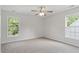 A bright, carpeted bedroom offers two windows for natural light and a ceiling fan for comfort at 8721 Springhouse Ln, Raleigh, NC 27617