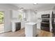 Modern kitchen featuring white cabinets, stainless appliances, an island, and hardwood floors at 8721 Springhouse Ln, Raleigh, NC 27617