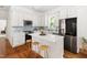 Bright kitchen features white cabinets, stainless steel appliances, and a center island with barstool seating at 1010 Cobb St, Durham, NC 27707