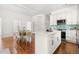 Open-concept dining room with white dining set connects to a bright kitchen with stainless steel appliances at 1010 Cobb St, Durham, NC 27707