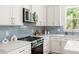 Close-up of a kitchen featuring white cabinets, blue backsplash, stainless steel microwave and countertops at 1010 Cobb St, Durham, NC 27707