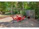 Beautiful backyard with a gravel area, red Adirondack chairs under a pergola, and lush greenery at 10608 Thornbury Crest Ct Ct, Raleigh, NC 27614