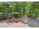 Backyard features a gravel area, vibrant red chairs under a pergola, privacy fence and mature trees at 10608 Thornbury Crest Ct Ct, Raleigh, NC 27614