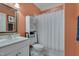 Cozy bathroom featuring a vanity, toilet, shower with white curtain, and vibrant coral walls at 10608 Thornbury Crest Ct Ct, Raleigh, NC 27614