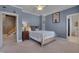 Bedroom with a wooden bed frame, grey walls, white trim, artwork and a staircase visible through the doorway at 10608 Thornbury Crest Ct Ct, Raleigh, NC 27614