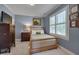 Comfortable bedroom with blue walls, a bed, a window with shutters, and decorative artwork at 10608 Thornbury Crest Ct Ct, Raleigh, NC 27614