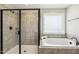 A modern bathroom features a tiled shower with glass door and a soaking tub next to a patterned window at 107 Southern Acres Dr, Fuquay Varina, NC 27526