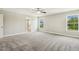 Large primary bedroom featuring plush neutral carpet, large windows, ceiling fan, and a doorway leading to the bathroom at 107 Southern Acres Dr, Fuquay Varina, NC 27526