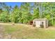 Large backyard with mature trees, fire pit, swing set, and storage shed with covered porch at 114 Cherryhill Dr, Four Oaks, NC 27524