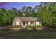 Charming single-story home featuring a cozy front porch, manicured landscaping, and a lush, wooded backdrop at 114 Cherryhill Dr, Four Oaks, NC 27524