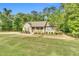 Welcoming single-story home with a lush green lawn, mature trees, and a cozy front porch, creating a serene setting at 114 Cherryhill Dr, Four Oaks, NC 27524