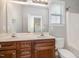 Well-lit bathroom featuring a double sink vanity with wooden cabinets, toilet, large mirror, and shower-tub combo for convenience at 141 Shad Boat Ln, Clayton, NC 27520