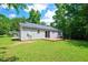 Exterior shot shows home with gray siding, small wood deck, a grassy yard, and natural surroundings at 144 Holly Mountain Rd, Holly Springs, NC 27540