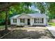 Charming single-story home featuring a covered front porch, manicured landscaping, and black window shutters at 144 Holly Mountain Rd, Holly Springs, NC 27540