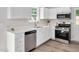 Modern kitchen features white cabinets, stainless steel appliances, quartz countertops, and stylish flooring at 144 Holly Mountain Rd, Holly Springs, NC 27540