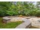 Lush backyard featuring flagstone patio with retaining walls and mature trees providing privacy at 15 Aman Ct, Durham, NC 27713