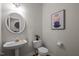 Well-lit powder room with pedestal sink, round mirror, and decorative artwork at 15 Aman Ct, Durham, NC 27713