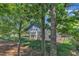 Private backyard featuring a covered patio, lush green grass, mature trees, and a black metal fence at 151 Cobble Ridge Dr, Pittsboro, NC 27312