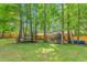 Large backyard featuring mature trees, a trampoline, seating area, playhouse, and above-ground pool at 1703 Keogh St, Burlington, NC 27215