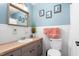 Bright bathroom featuring a wood countertop, framed mirror, gray vanity, and classic white tiled walls at 1703 Keogh St, Burlington, NC 27215