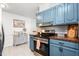 Charming kitchen features custom blue cabinets, herringbone backsplash, butcher block countertops, and stainless steel appliances at 1703 Keogh St, Burlington, NC 27215