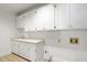 Functional laundry room with white cabinets, countertops, and tile flooring at 201 Red Bud Ln, Chapel Hill, NC 27514