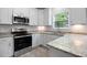 Bright kitchen features modern stainless steel appliances, granite countertops, and white cabinets at 208 W Holt St, Burlington, NC 27217