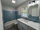 Updated bathroom featuring a white vanity and blue tiled shower at 213 N Brevard St, Selma, NC 27576