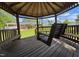 Inside the wooden gazebo featuring a swing bench and bench seating with open views of the backyard at 213 N Brevard St, Selma, NC 27576