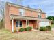 Traditional brick home with a two-car garage, covered porch, tidy landscaping, and symmetrical window placement at 2193 Boyd Creek Dr, Graham, NC 27253