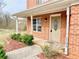 Inviting brick home entrance with a covered porch, manicured shrubs, and a decorative front door with glass at 2193 Boyd Creek Dr, Graham, NC 27253