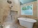 Bright bathroom featuring a free-standing tub, stone floors, and a rain shower-head at 266 Hogans Valley Way, Cary, NC 27513