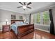 Serene bedroom boasts hardwood floors, a large window, ceiling fan and a classic wood bed frame at 266 Hogans Valley Way, Cary, NC 27513